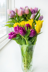 A beautiful bouquet of colorful spring tulips stands on the window. Close-up