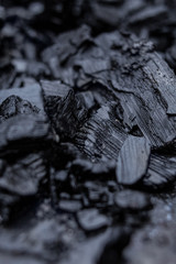 Close-up burnt wood coals is lying on the ground and is wet from the rain that has since started