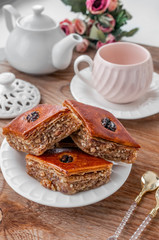 Traditional arabic dessert baklava with a cup of coffee, cashews, walnuts and cardamom on a wooden table. Homemade Baklava with Nuts and Honey
