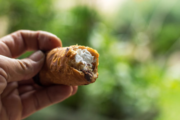 man hand holding a cream filled pastry shallow depth of field