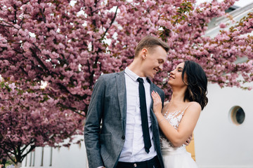 happy bride and groom hug and kiss on the street near the tree