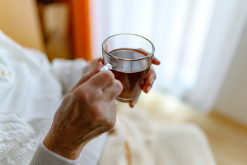 Rentnerin bekommt von der Pflegekraft ein Glas Tee gereicht
