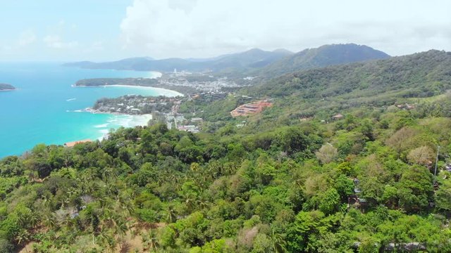 AERIAL: Flying over forest in Phuket, with a view of the sea and a beach.