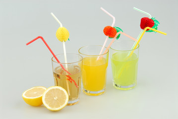 Three mason jar glasses of summer lemonade, and green, orange lemonade drinks, lemon, isolated on a gray background