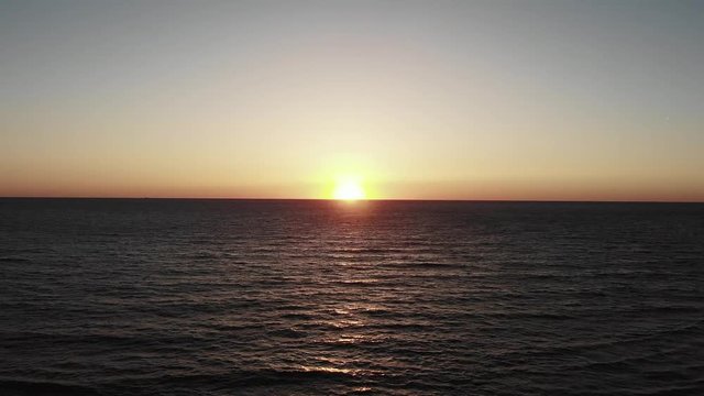 Sunset aerial drone shot of mediterranean sea. Sea waves sky and sun on horizon. Cinematic drone shot.