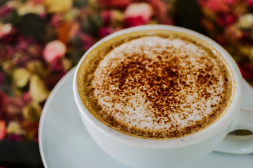 Hot mocha coffee sprinkled with cocoa powder on a glass table.