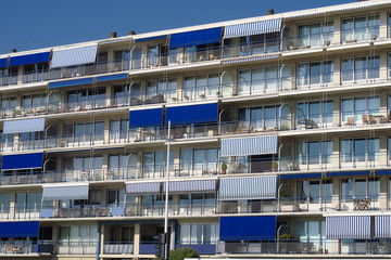 Immeuble avec balcons et stores bleus et rayés