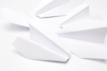 Flat lay of white paper planes on white background.