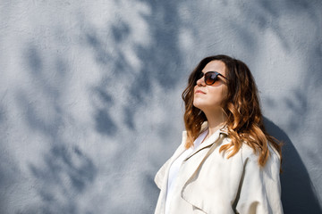 A young, sympathetic woman, not a thin-headed body building, stands on the background of the wall. Business clothing style.