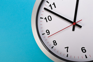 Closeup wall clock set on blue background. The concept of 