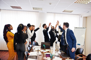 Multiracial business people standing at office and give high five each other. Diverse group of...