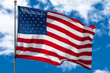 American Flag blowing in front of blue sky with clouds