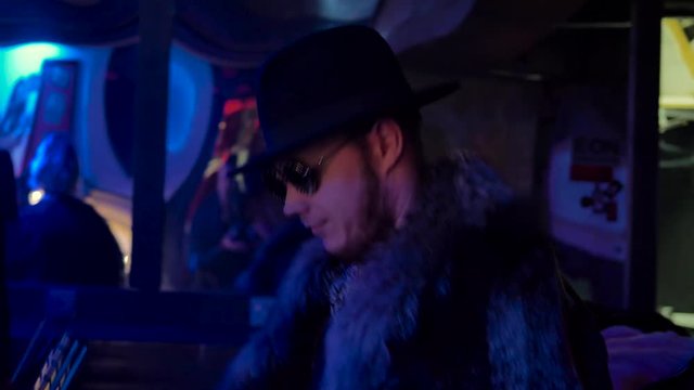 a man with a beard, wearing a hat, a fur coat, round glasses, a cane in his hand, dancing in a nightclub