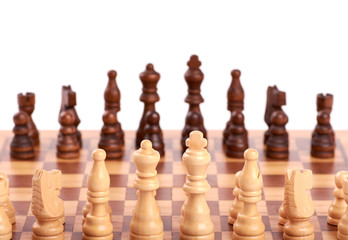 Set of white and black wooden chess pieces standing on a chessboard, isolated on white background