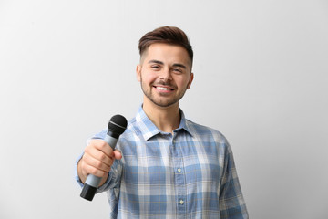 Naklejka premium Handsome man with microphone on light background