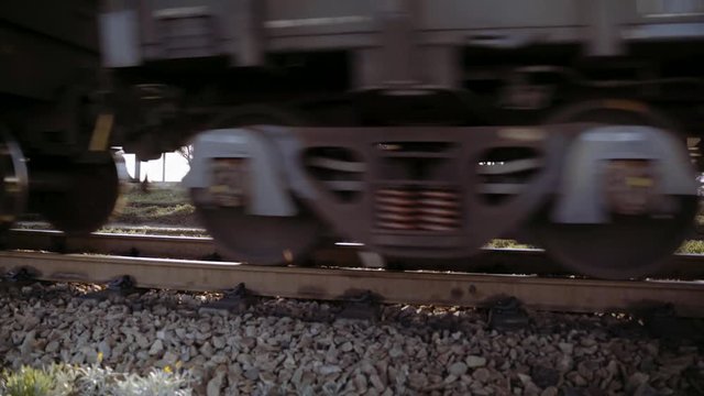 Close up of train wheels and wagons of an ore train pass by the camera.