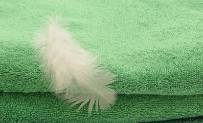 Folded towel and bird feather as symbol of freshness