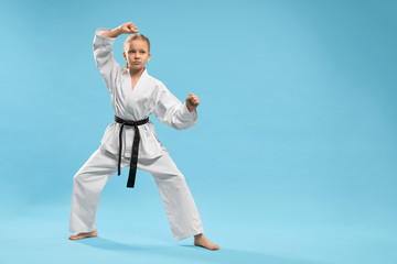 Sporty girl standing in stance and training karate in studio