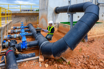 Manual worker turning big valve in industrial plant