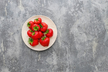 Plate with strawberries on grey stone background