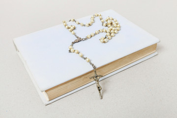 Holy Bible and white rosary.
