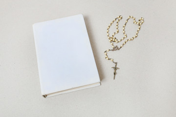 Holy Bible and white rosary.