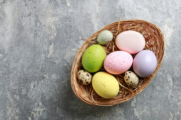 Basket of colorful Easter eggs on grey, stone background.