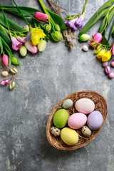 Basket of colorful Easter eggs on grey, stone background.