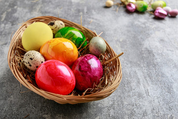 Basket of colorful Easter eggs on grey, stone background.