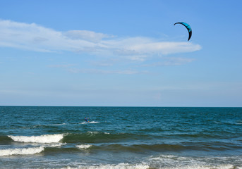 People fly by parachute against blue sky