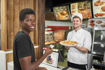 Male client looking at camera while buying delicious pizza