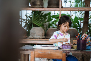 Fototapeta na wymiar child painting on white fabric. asian kid learn to make batik