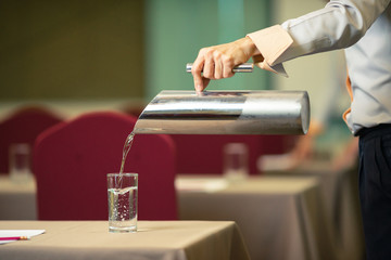 Hotel staff who are Pour drinking water into the glass in the seminar room.
