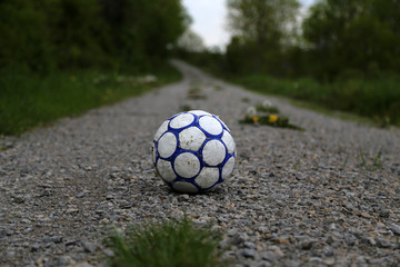 Fototapeta na wymiar Old football ball lies on the road