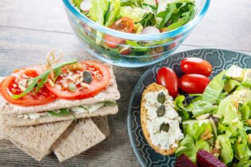 bowls and plate of healthy vegan salad. Various vegetables on wooden background