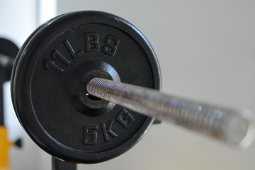 Close up of side view of 5 Kg. barbell on the rack in fitness gym. Weight Training Equipment....