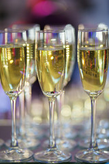 row of transparent glasses with champagne on a rack in a bar or restaurant prepared for guests of festive events.