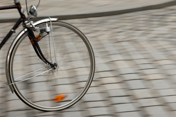 Fototapeta na wymiar Bike wheel on cobblestoned street.