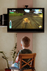 Little child playing video game at tv with game console
