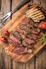 Juicy medium rare beef steak on wooden board with herbs and spices.