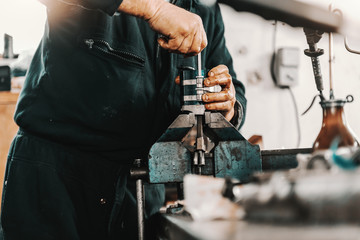 Auto mechanic adjusting cylinder on clamp while standing at workshop.