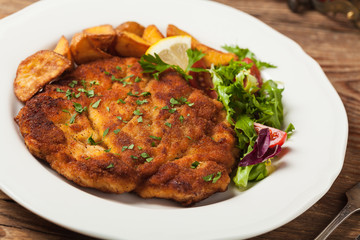 Chicken schnitzel, served with roasted potatoes and salad.