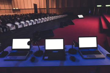 business laptop and microphotone at podium in seminar room with attendee background, Business meeting concept
