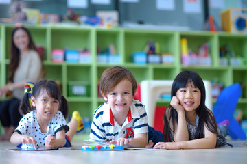 Obraz na płótnie Canvas group of international kids in preschool enjoy reading books with teacher watching in back ground
