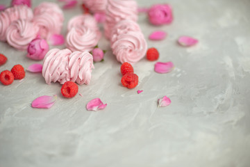 Rose and rose petals, raspberries, homemade pink marshmallows on a concrete background