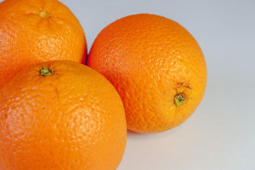 Three whole ripe oranges in a group on a white background close-up.