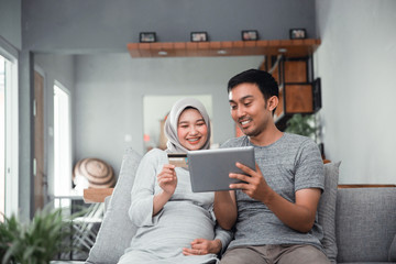 asian muslim couple buy and do payment using credit card while online shopping on market place