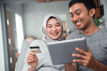 asian muslim couple buy and do payment using credit card while online shopping on market place