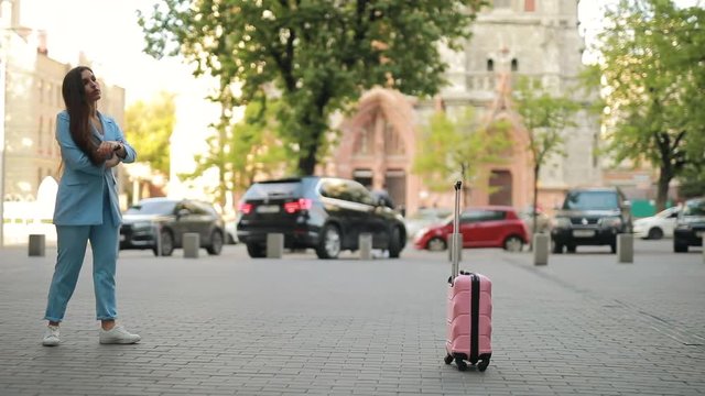 Distracted forgetful woman waiting taxi in city and forget her suitcase