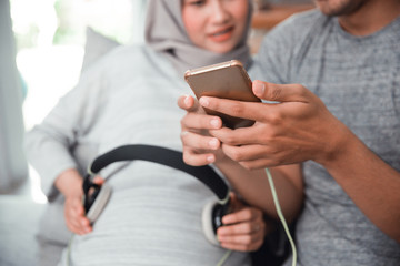 muslim pregnant woman with headphone on her belly, listening music to her baby inside her tummy